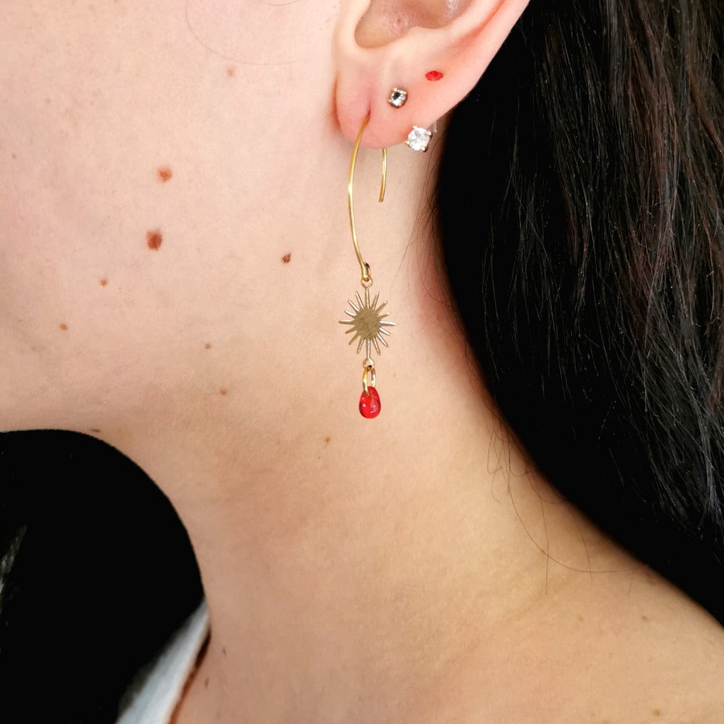 Boucles d'oreilles en laiton brut avec soleil et petite perle rouge portée 