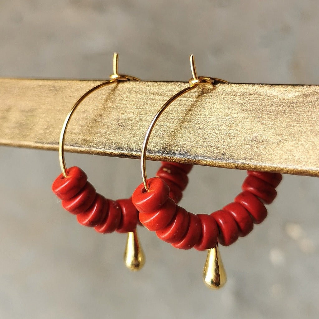 Boucles d'oreilles créoles avec perles d'howlite teintée rouge et gouttes dorées composées en Belgique
